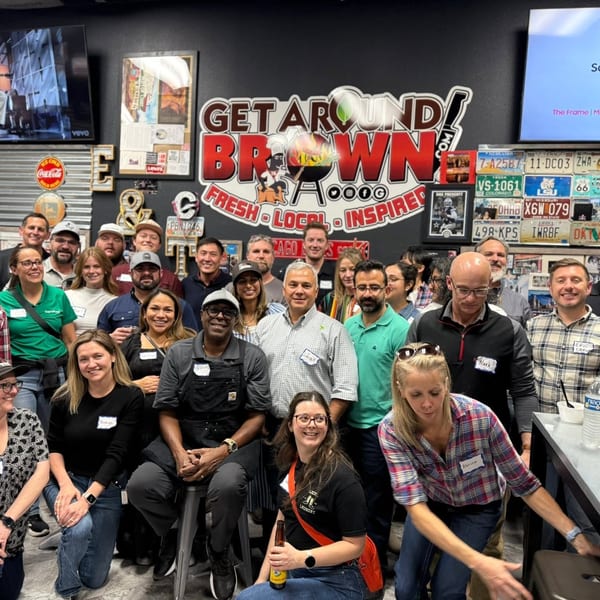 A large group of smiling people gathered in front of a "Get Around Brown" sign.